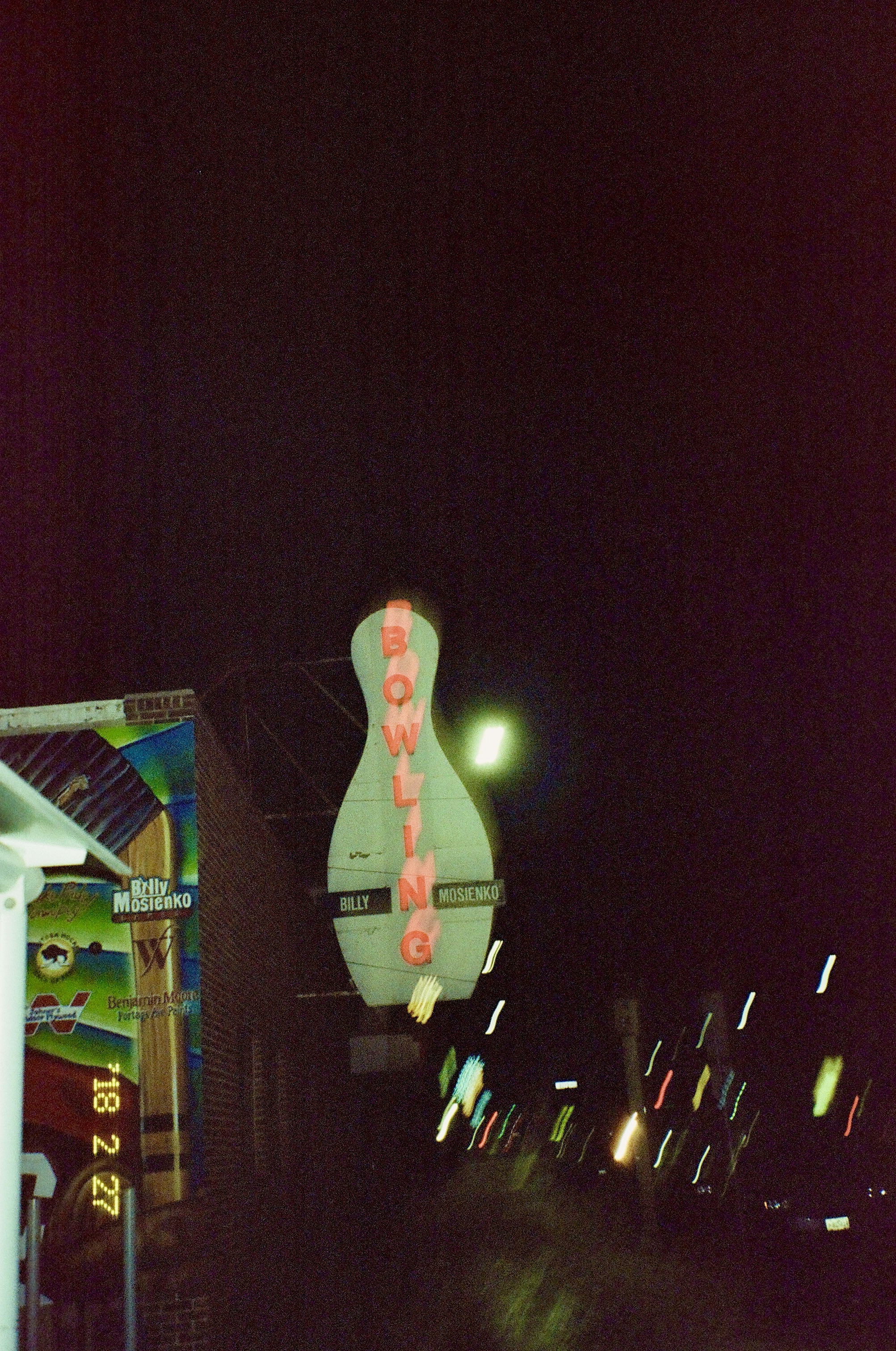 a dark street with a bowling alley sign